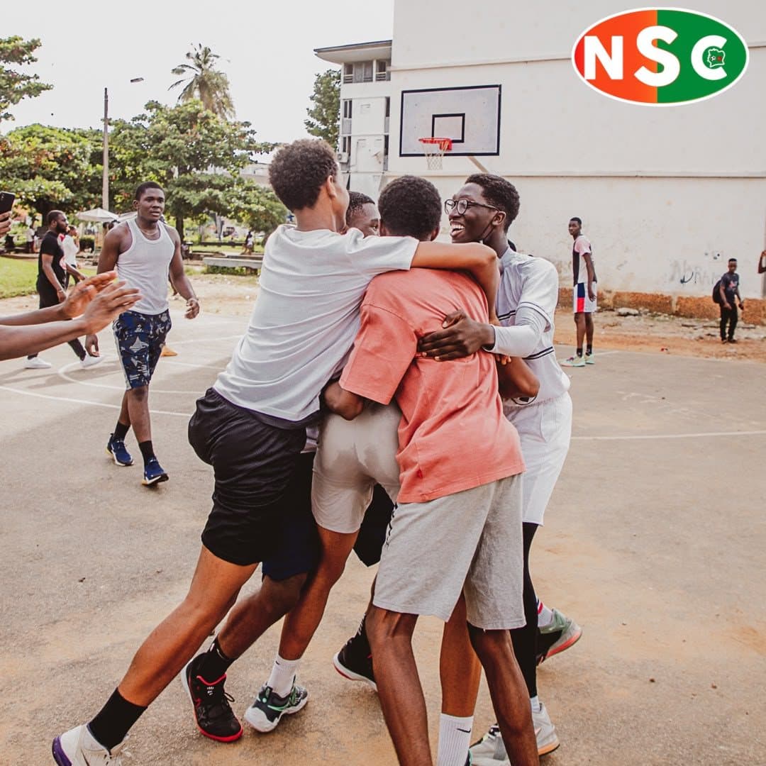 Des joueurs se prennent dans les bras après un panier, sur un playground d'Abidjan