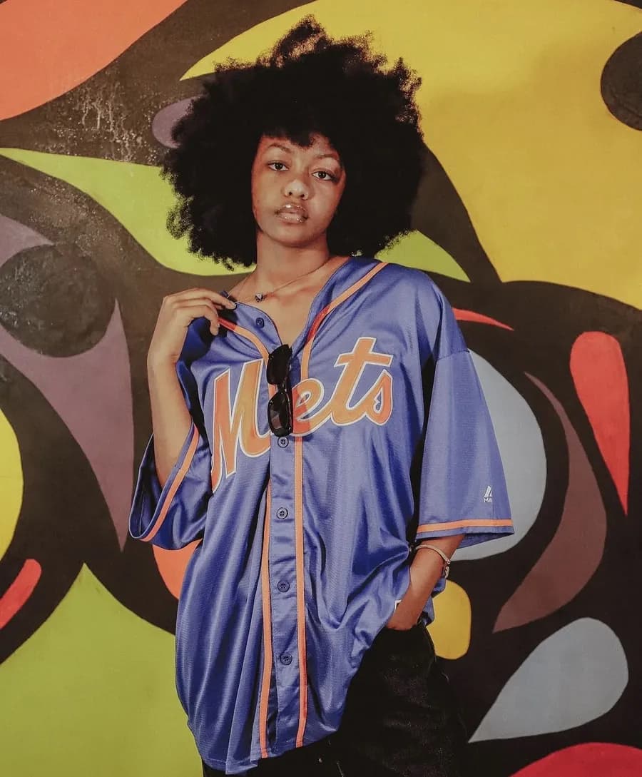 Une jeune femme porte un maillot de baseball Mets devant une fresque
